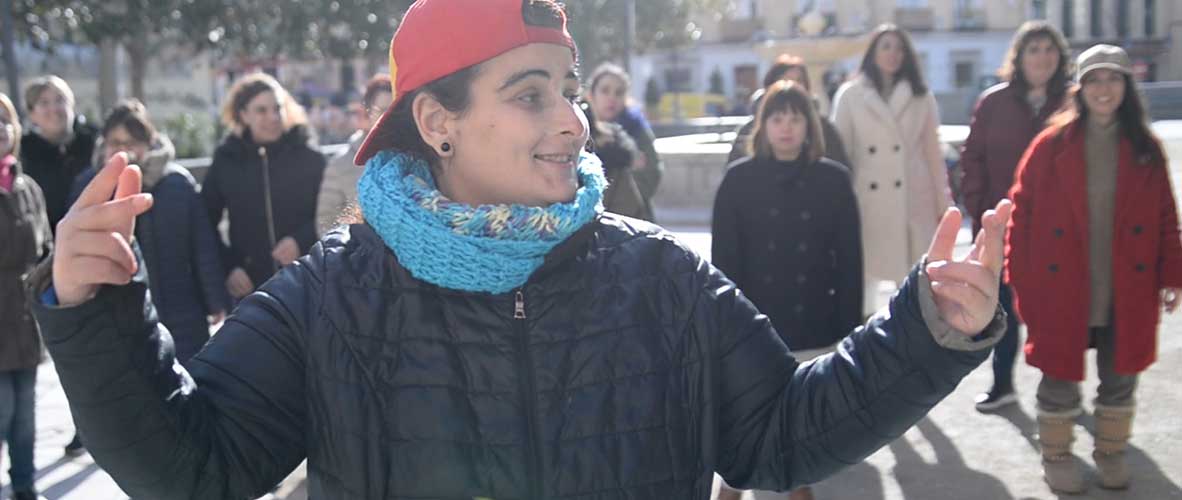 Una mujer con discapacidad en primer plano, rapeando