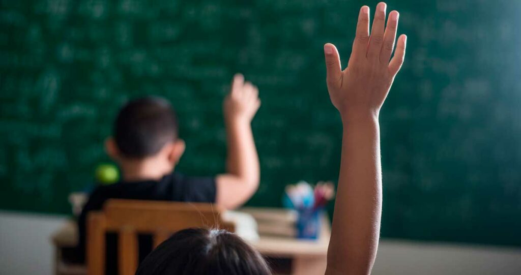 Alumno en colegio con la mano levantada