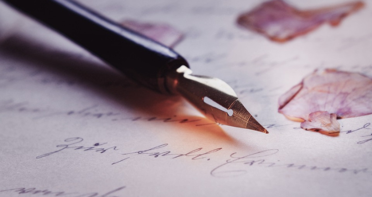 Pluma sobre folio con letras escritas