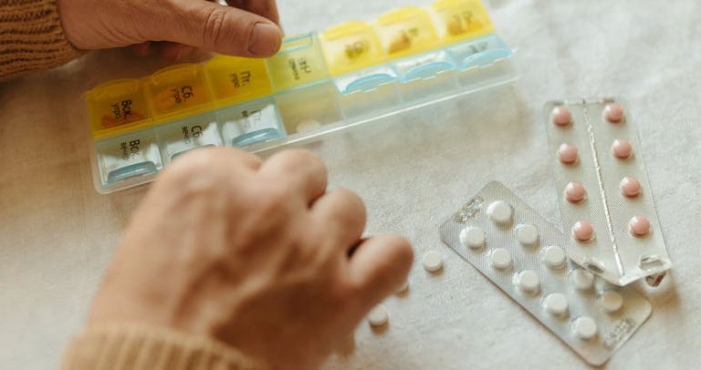 Persona organizando los medicamentos en el pastillero