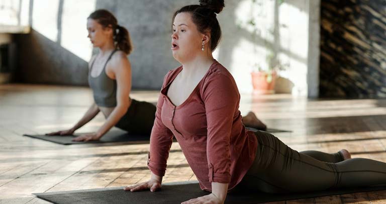 Jóven con síndrome de Down haciendo yoga en espacio comunitario
