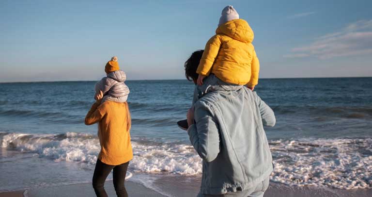 Familia paseando por la playa en invierno